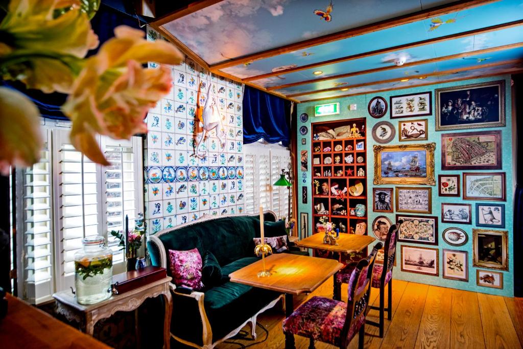 阿姆斯特丹Rosalia's Menagerie Cocktail bar & InnUpstairs的一间设有绿色沙发和桌子的客房,墙上挂有图片