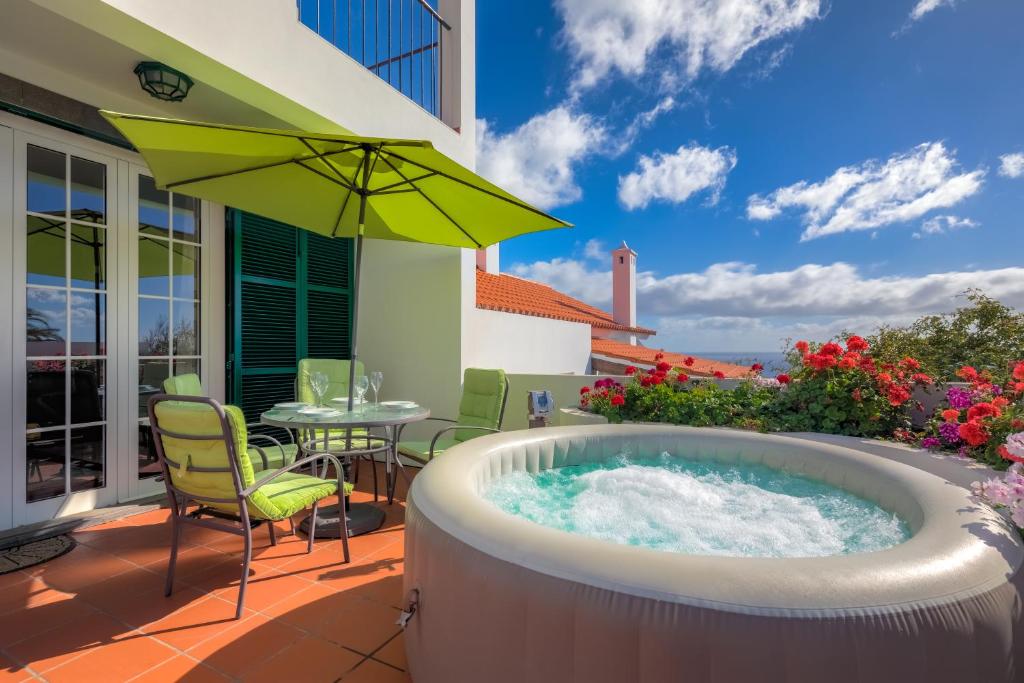 卡尼索Villa Atalaia by HR Madeira的庭院内的热水浴池,配有桌椅