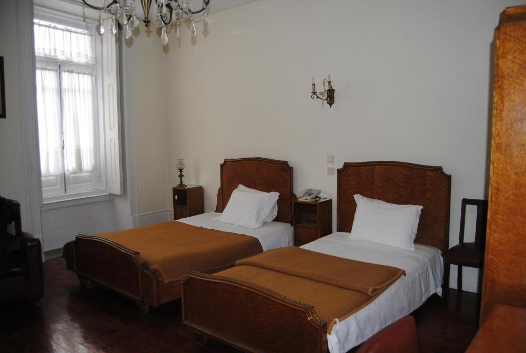 波尔图Hotel Peninsular- Porto的一间卧室配有两张床和吊灯。