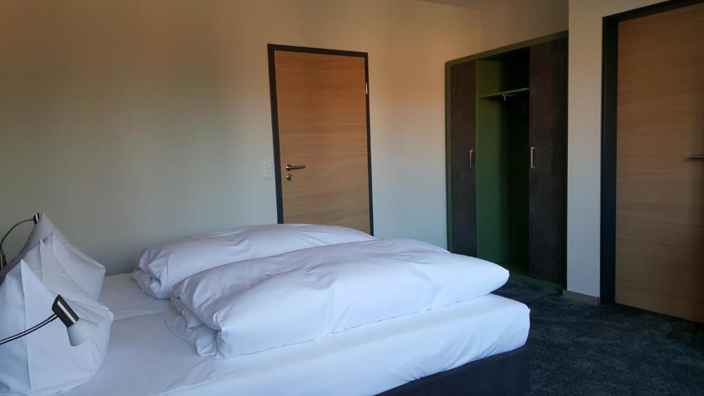 Großefehn Hotel Landhaus Feyen的配有两扇门的房间的一张白色床