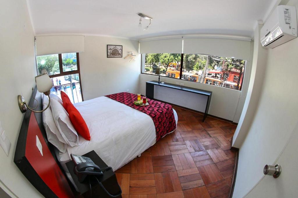 圣地亚哥Hotel Plaza Ñuñoa的一间卧室配有一张床、一张书桌和两个窗户。