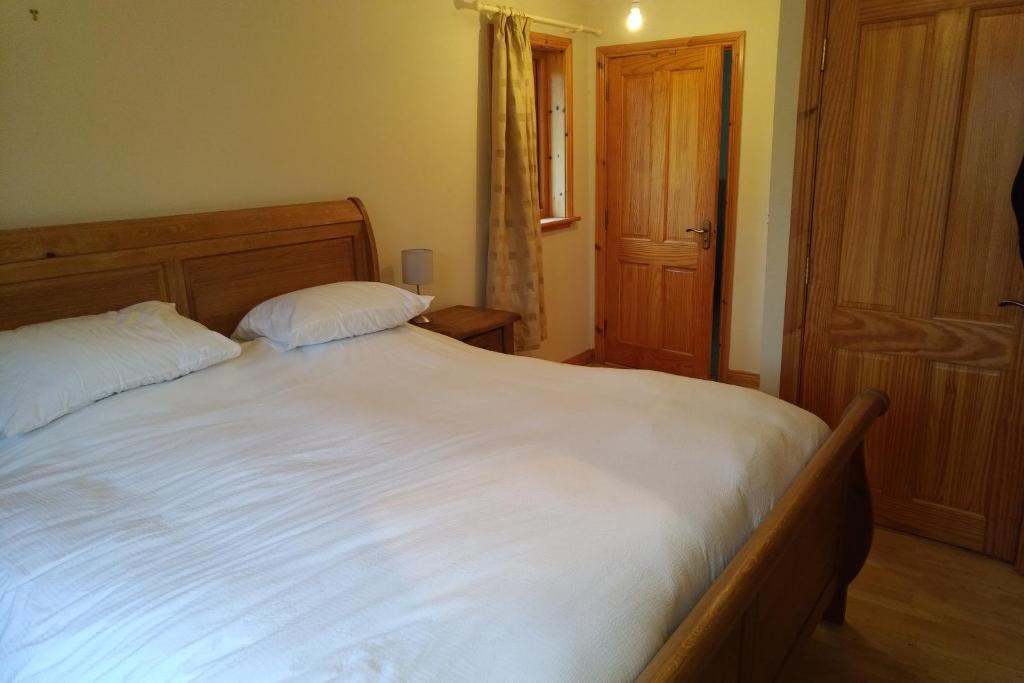 巴利纳莫尔14 Drumcoura Lake Resort的卧室配有一张带两个枕头的大白色床