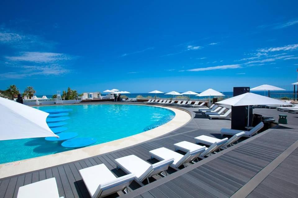 韦尔都勒博Modern 2 Bed Apartment Vale do Lobo的一个带白色躺椅和遮阳伞的游泳池