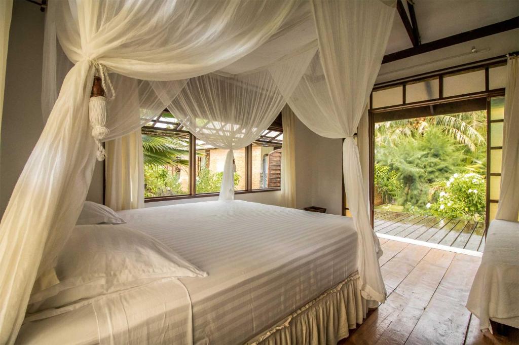 阿瓦托鲁Le Coconut Lodge的卧室配有白色的床和窗户
