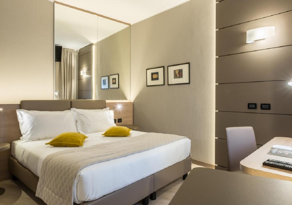 卡尔达诺阿尔坎波马尔彭萨卡达诺酒店的一间卧室配有一张带黄色枕头的床和一张书桌