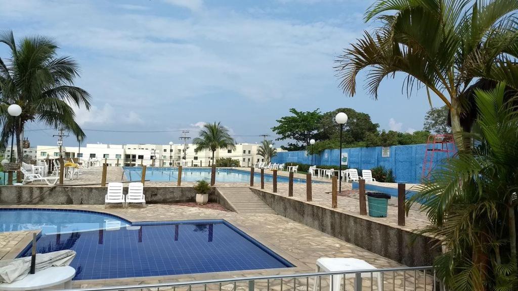 圣佩德罗-达阿尔德亚Apartamento em Condomínio Marinas Clube的一个带椅子和棕榈树的度假游泳池