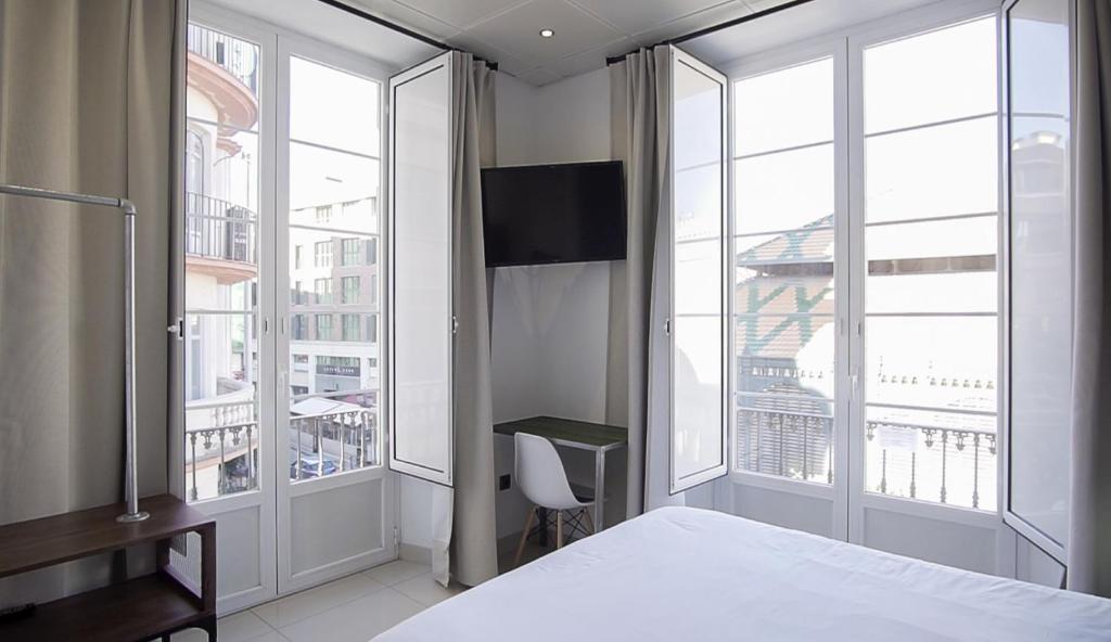 马拉加The Lights City Rooms的一间卧室设有一张床和两个大窗户