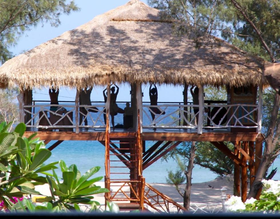 吉利特拉旺安日落海滩别墅酒店的海滩上带茅草屋顶的树屋