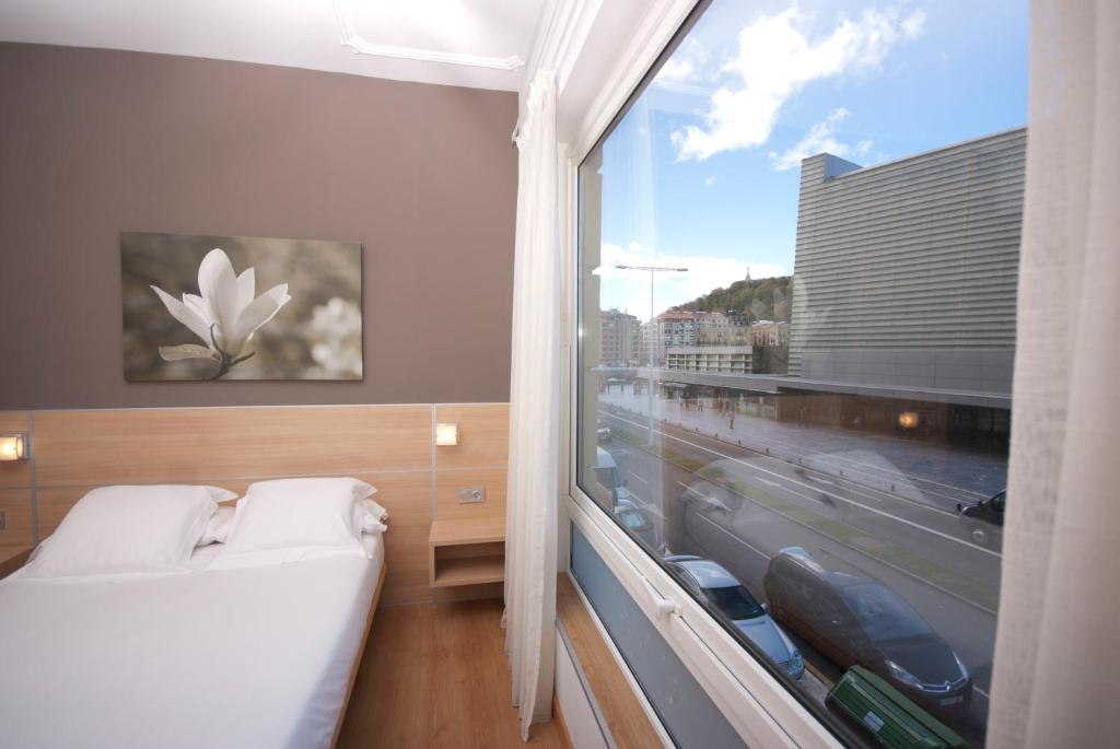 圣塞瓦斯蒂安库尔萨尔酒店的一间卧室设有一张床和一个大窗户