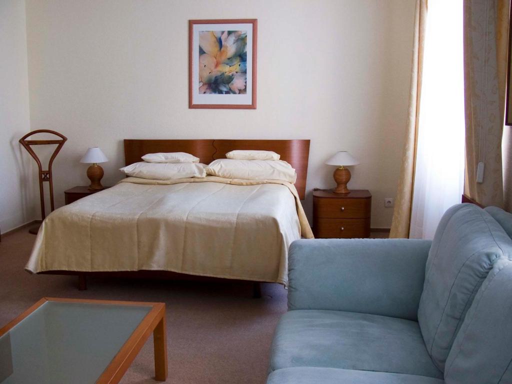 多瑙新城克鲁博酒店的一间卧室配有一张床和一张蓝色的沙发