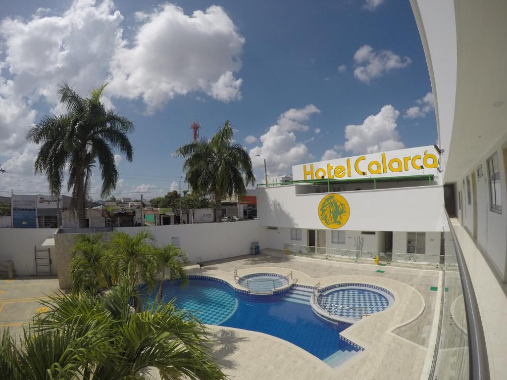 蒙特里亚Hotel Calarca Club的一座拥有游泳池和棕榈树的酒店建筑