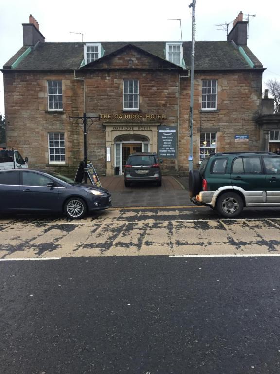 阿普海尔奥特里奇酒店的两辆汽车停在砖楼前