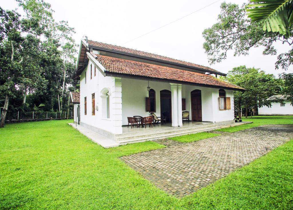 阿杭格默Villa Indrasiriya的一座带草地庭院的白色小房子