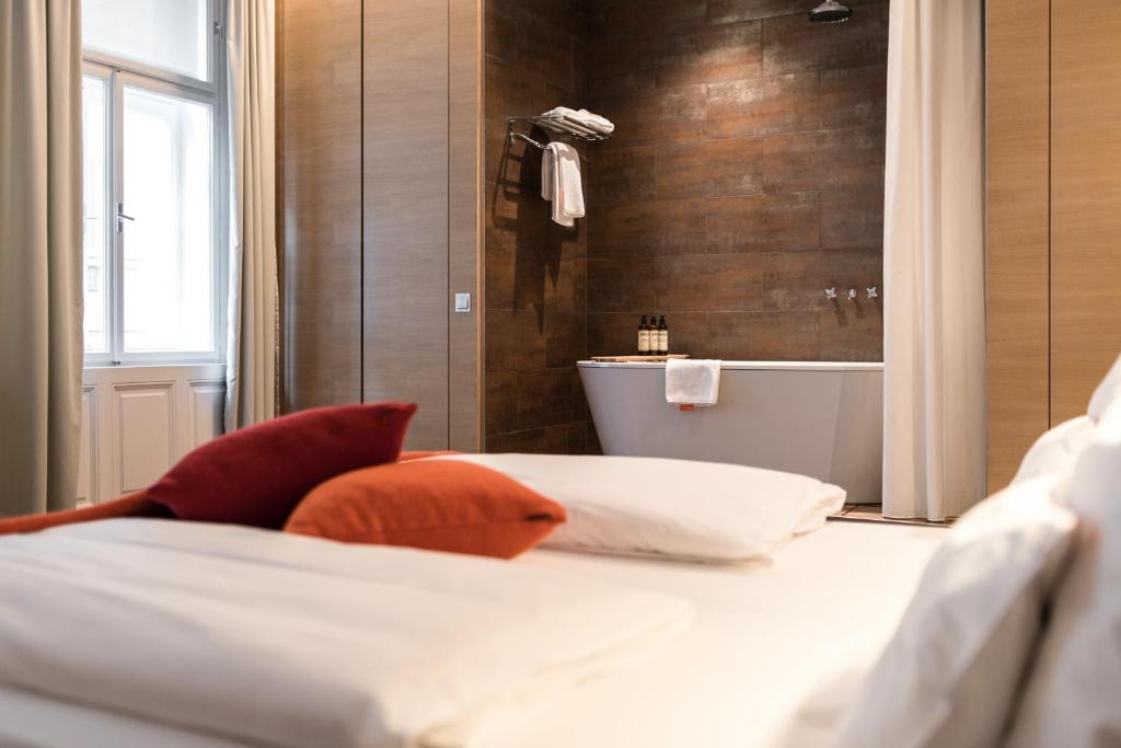 维也纳霍尔曼贝勒塔格设计精品酒店的一间带一张床和浴缸的卧室以及一间浴室