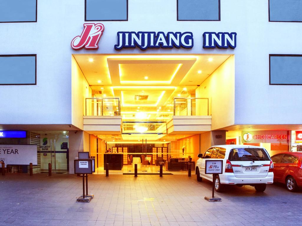 马尼拉Jinjiang Inn - Makati的前面有停车位的建筑