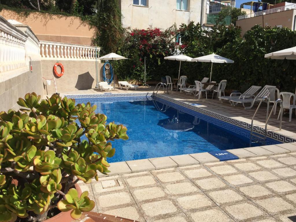 马略卡岛帕尔马圣特尔莫旅馆的一个带桌椅和遮阳伞的游泳池