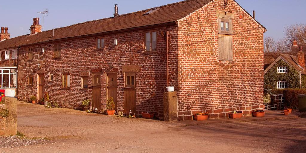 威勒尔The Old Mill Barn with Hot Tub and Private Pool的一座砖砌的旧建筑,前面有盆栽植物