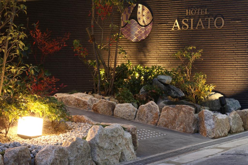 大阪Tabist Hotel Asiato Namba的一座花园,在一座建筑前有岩石和植物