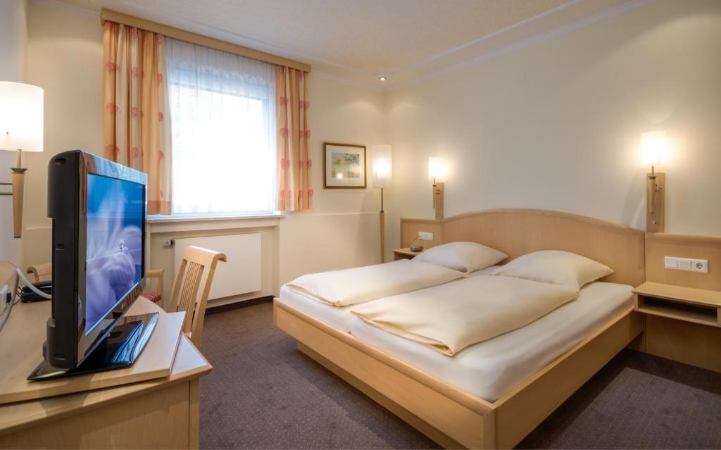 慕尼黑嘎斯霍夫祖尔博斯特酒店的一间卧室配有一张床和一张书桌上的电视