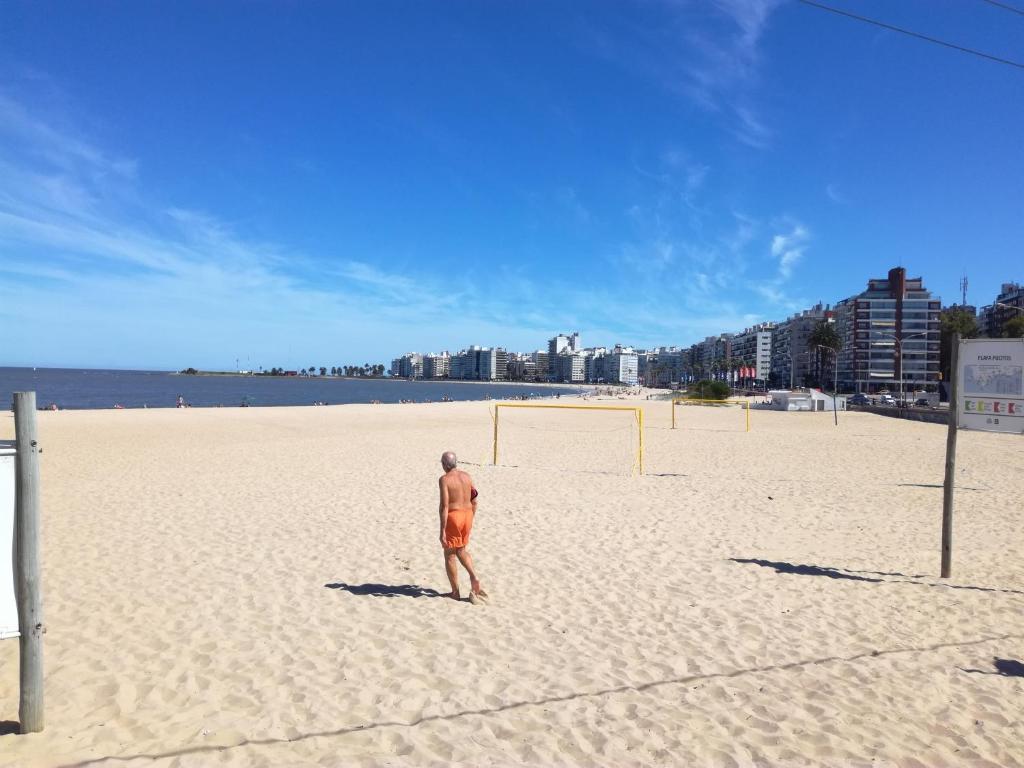 蒙得维的亚Stone Wasi的一名男子站在海滩上,手持足球球
