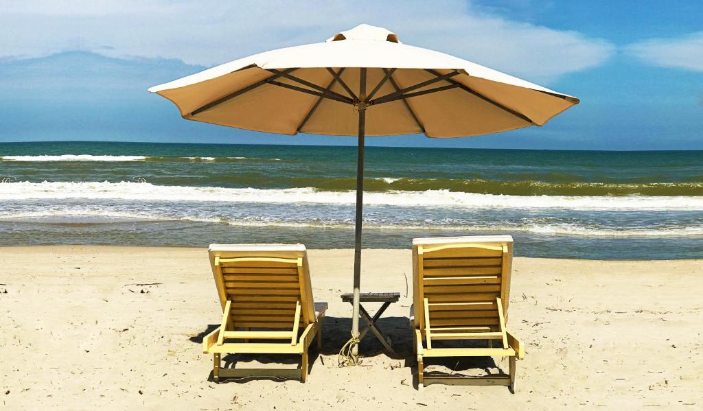 会安柯波恩海滨住宿加早餐旅馆的海滩上的两把椅子和一把遮阳伞
