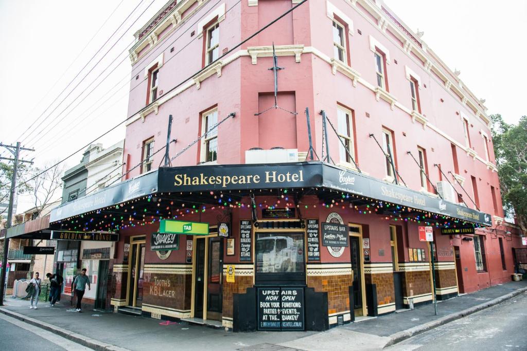 悉尼莎士比亚酒店的街道上一座粉红色的建筑,有摇摆的旅馆