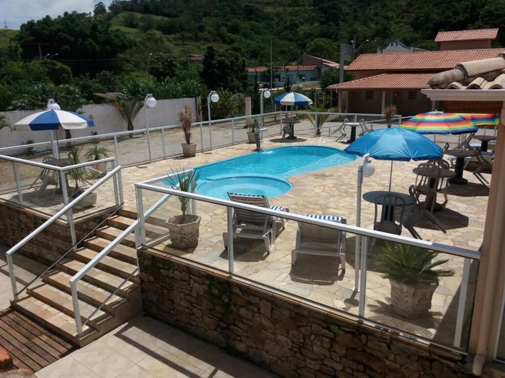 塞拉内格拉Pousada Encantos da Serra的一个带椅子和遮阳伞的大型游泳池