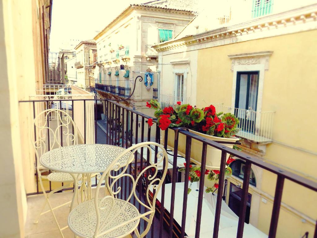 拉古萨L'arco delle Commari的阳台配有桌椅和鲜花。
