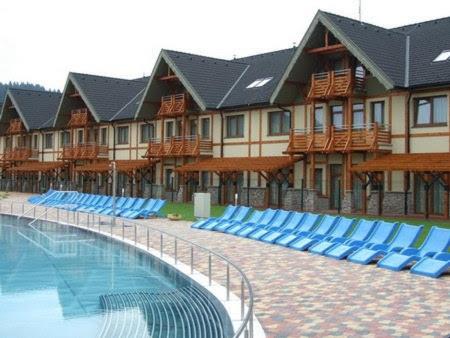 贝谢诺瓦Wellness Hotel Bešeňová的一个带蓝色躺椅和游泳池的度假村
