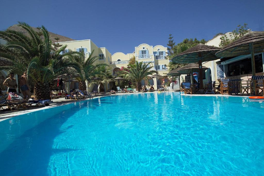 卡马利泽菲罗斯酒店的一座种植了棕榈树和建筑的大型蓝色游泳池