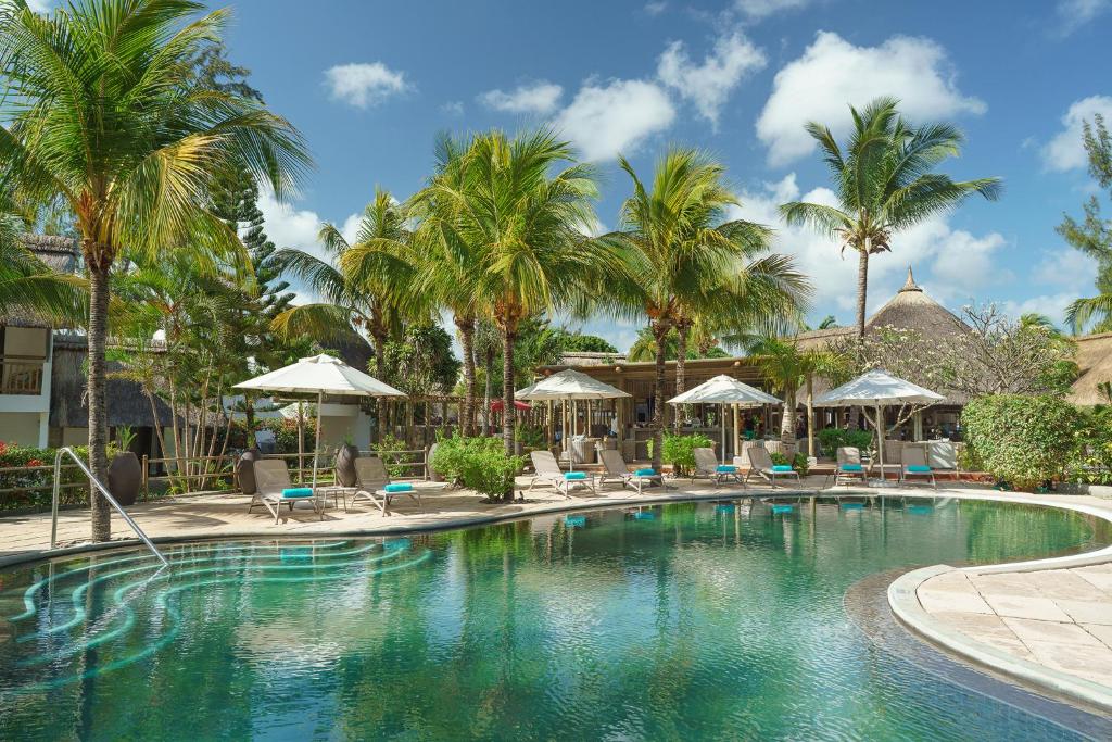 马勒勒角考恩沼泽地酒店的棕榈树和椅子的度假村的游泳池