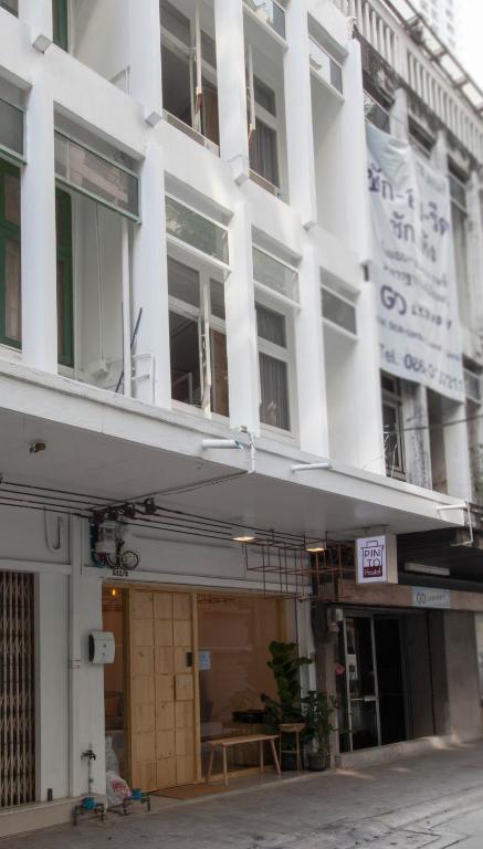 曼谷平托青旅的街道上一栋带阳台的白色建筑