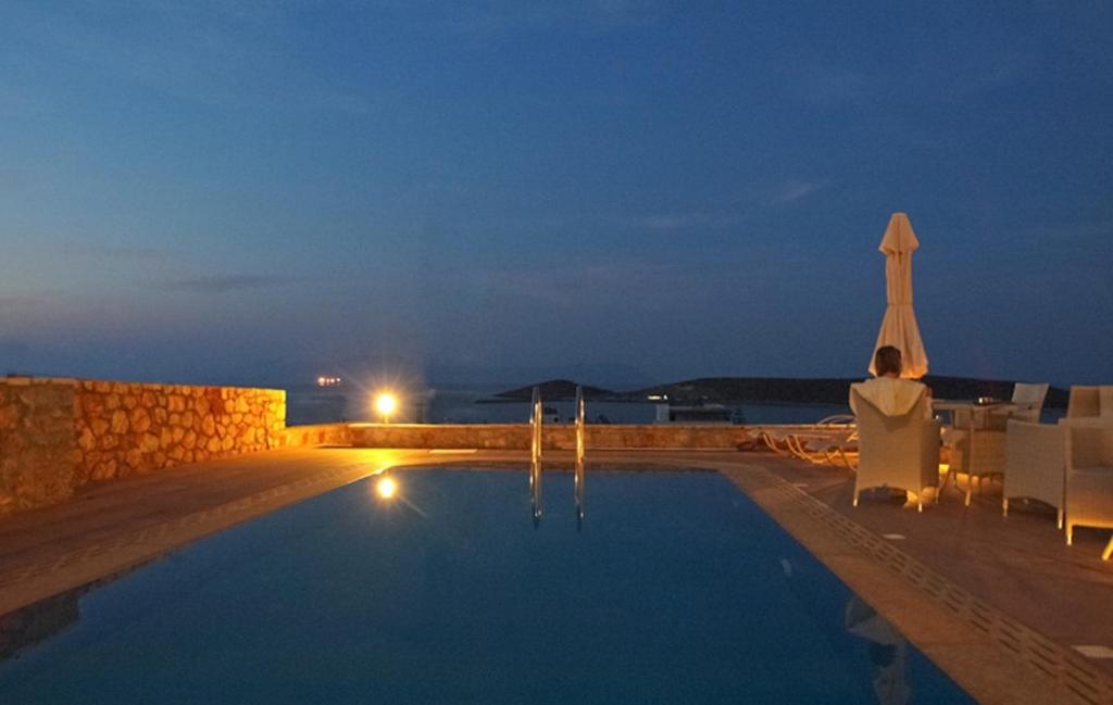 DiakoftiKythira Golden Resort的夜间游泳池,配有椅子和遮阳伞
