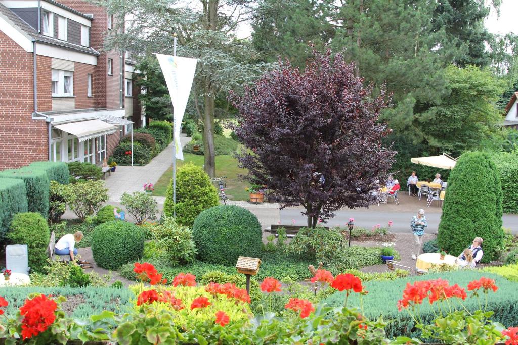 利普施塔特Hotel-Pension Haus Holtdirk的种满鲜花的花园,人们坐在桌子旁