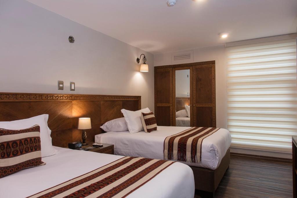 奥兰太坦波Del Pilar Ollantaytambo的酒店客房设有两张床和窗户。