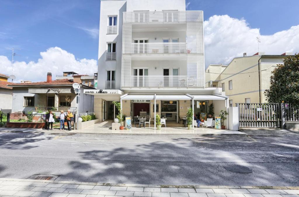 福洛尼卡拉毕内塔酒店的一座白色的建筑,前面的人站在