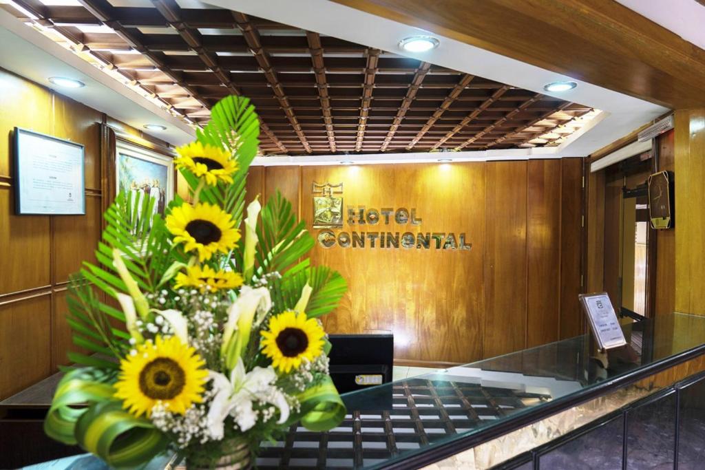 卡哈马卡Hotel Continental (Cajamarca)的花瓶里满是向日葵,坐在大堂