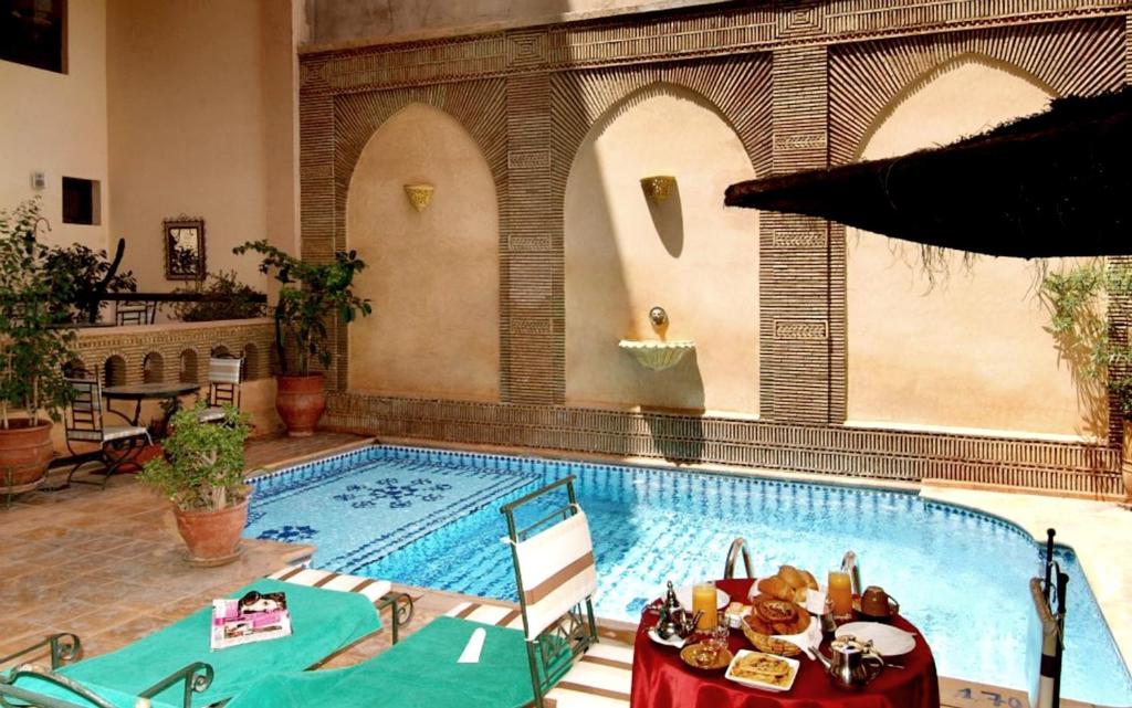 马拉喀什Amani Hotel Suites & Spa的前面设有一张桌子的大型游泳池