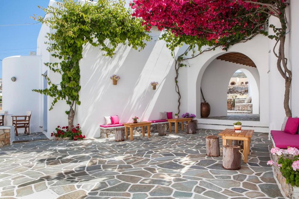 乔拉弗雷恩多斯Aegeo Hotel的白色墙壁上带粉色家具和鲜花的庭院