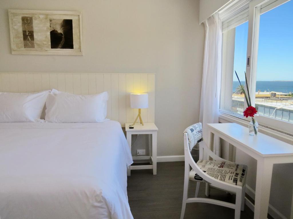 埃斯特角城Atlántico Boutique Hotel的一间卧室配有一张床、一张书桌和一个窗户。