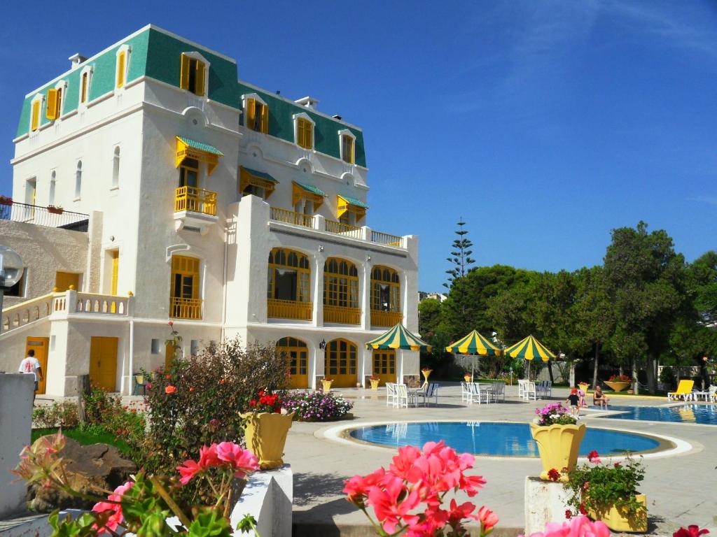 塔巴卡Hôtel LES MIMOSAS TABARKA的一座白色的大建筑,前面设有一个游泳池