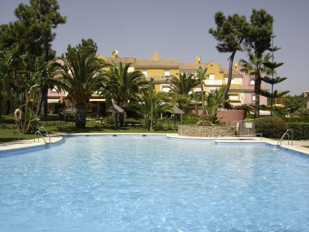 伊斯兰蒂拉Magnífico adosado de esquina con vistas al golf playas Islantilla的棕榈树度假村内的大型游泳池