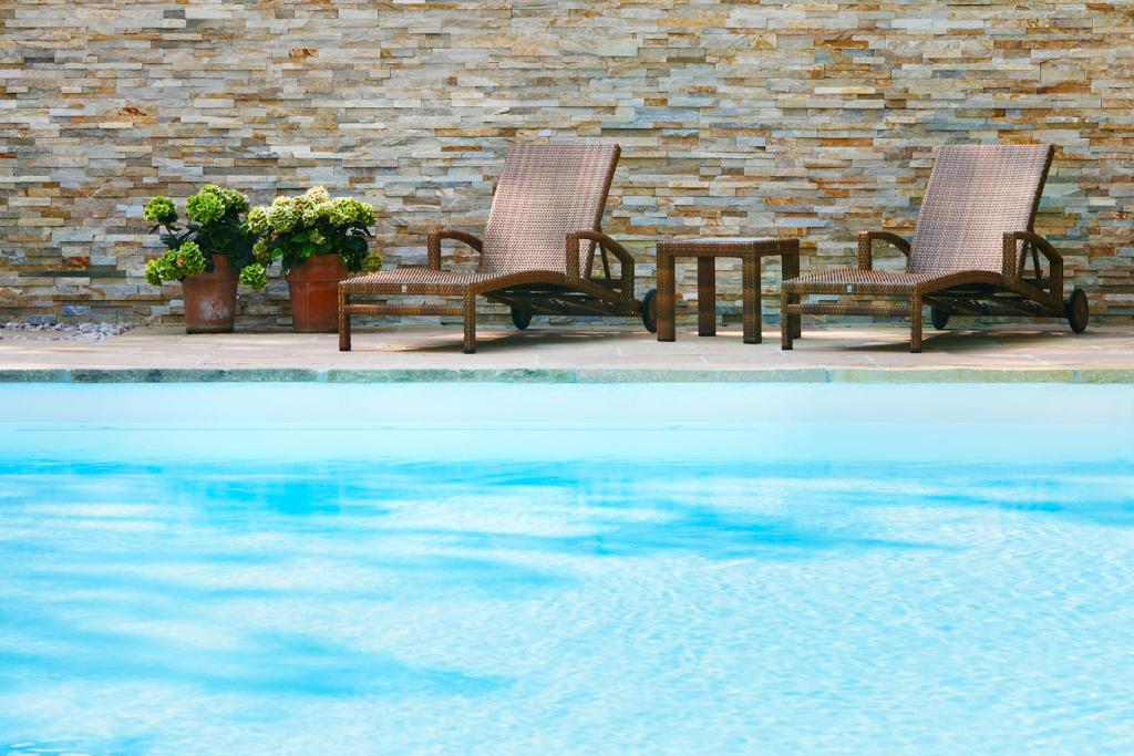 巴特贝林根马库斯霍库酒店的游泳池畔的两把椅子和一张桌子