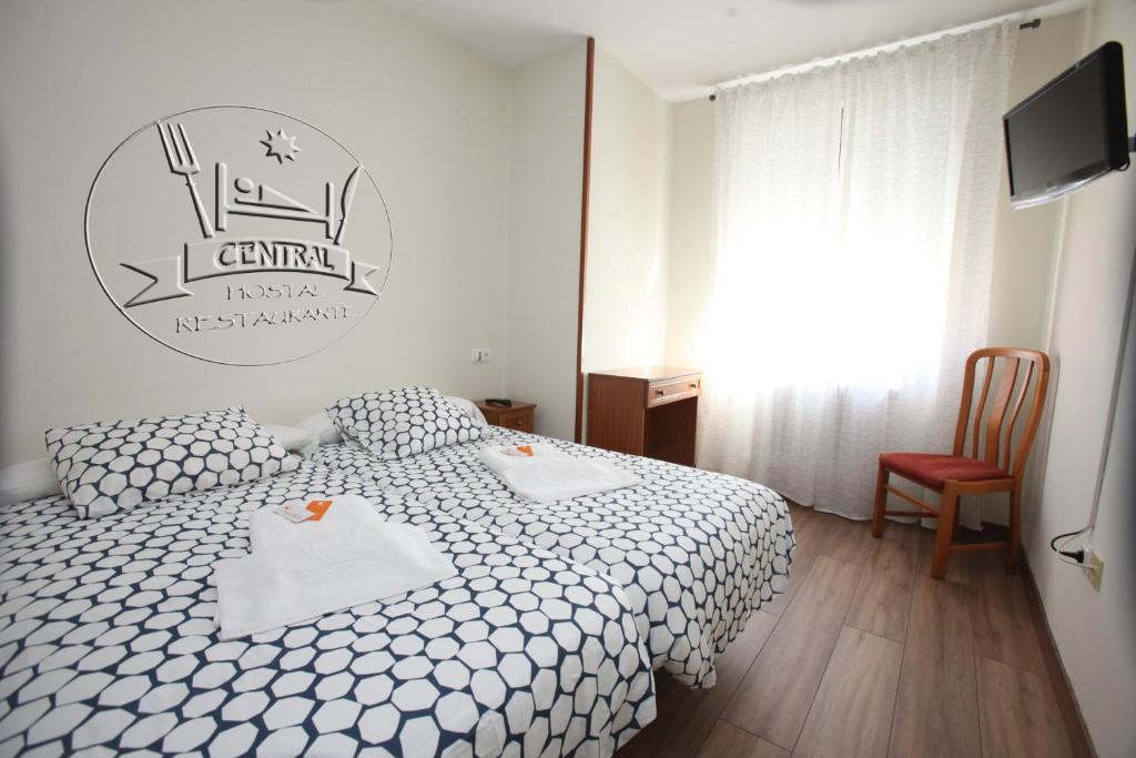 维尔根德尔卡米诺Hostal Restaurante Central的卧室配有白色的床和电视