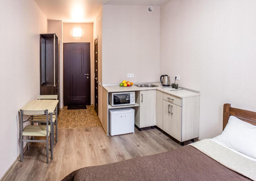 哈尔科夫Apart Hotel Smart Studio的一间设有床铺、厨房和桌子的房间
