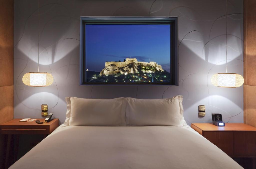 雅典尼欧酒店的卧室配有一张床,墙上配有电视。