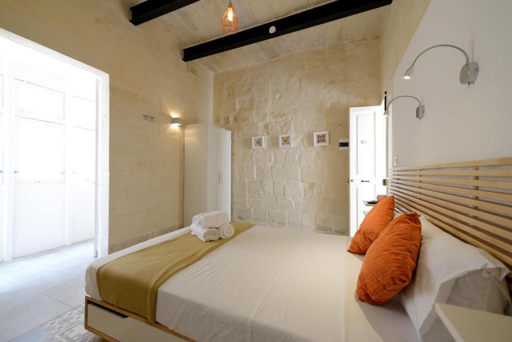 瓦莱塔Vallettastay Lovely House Private Rooms的一间卧室配有一张带橙色枕头的大床