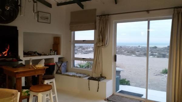 KleinseeBeach Cottage Kleinzee的客房设有书桌和享有海滩景致的窗户。