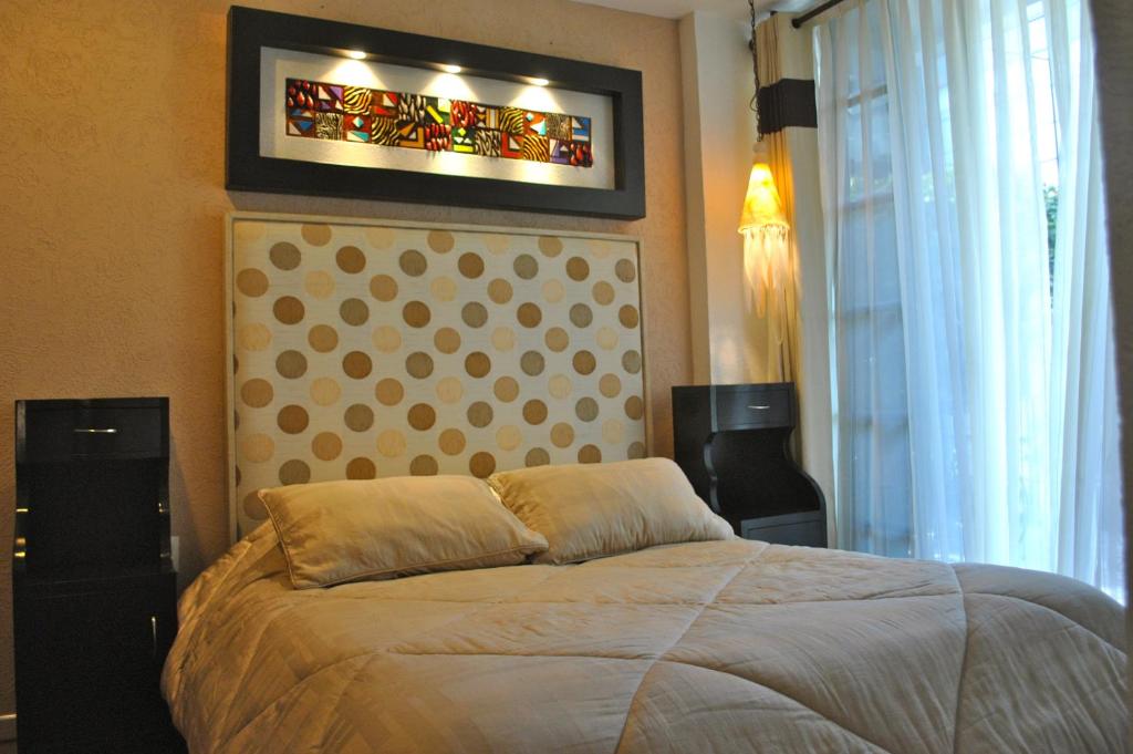 墨西哥城商务套房SG酒店的一间卧室设有一张床和一个彩色玻璃窗