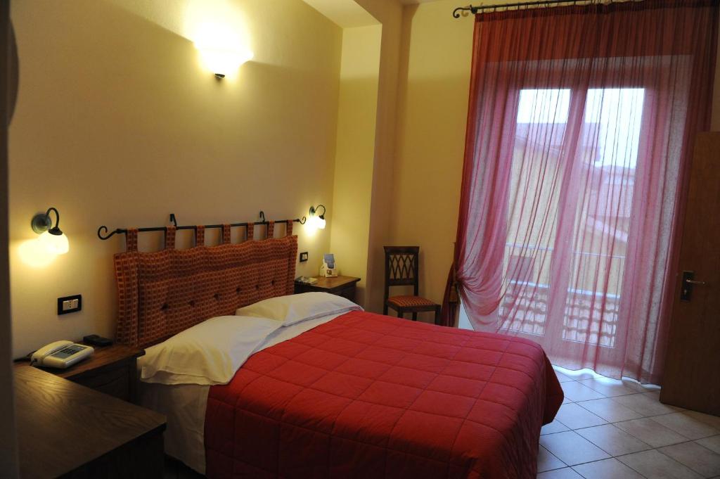 曼恰诺罗西酒店的一间卧室配有红色的床和红色毯子